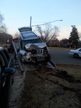 Damaged SUV being towed after accident.
