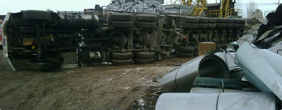 Overturned train cars lying on their side near a parked vehicle.