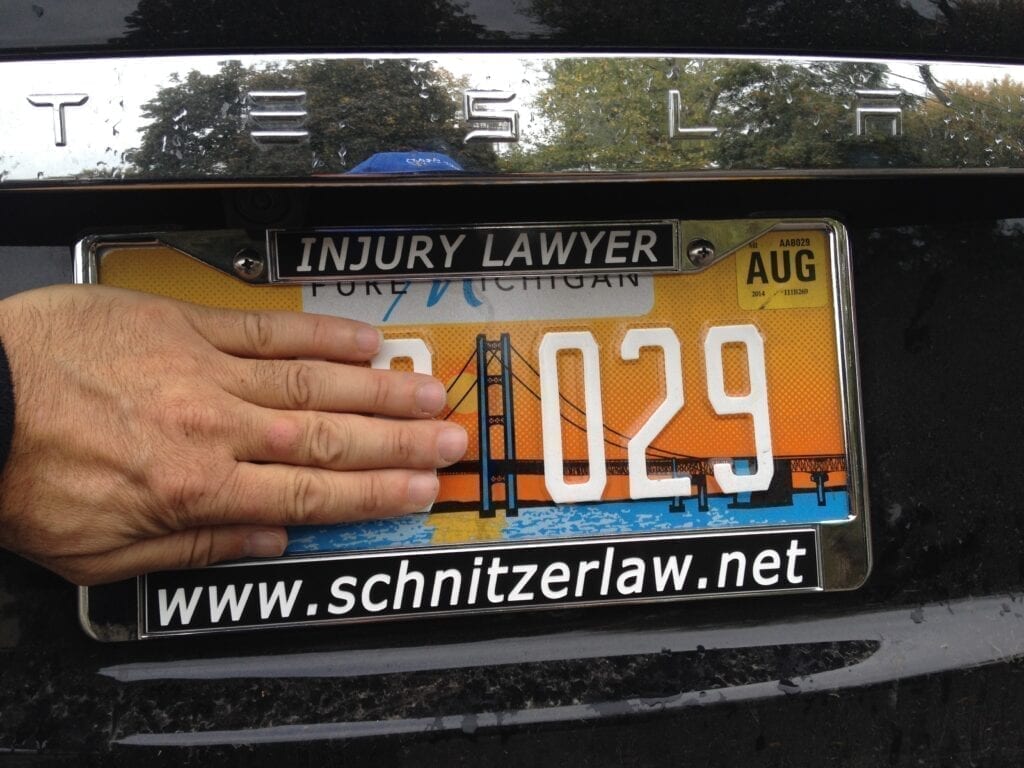 Hand covering part of a Tesla license plate.